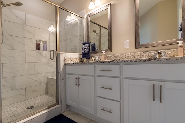 full bathroom featuring double vanity, a stall shower, marble finish floor, and a sink