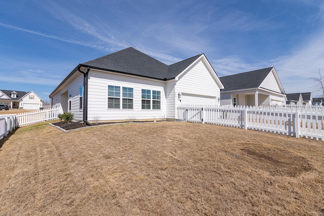 back of house featuring a garage, a lawn, and a fenced backyard