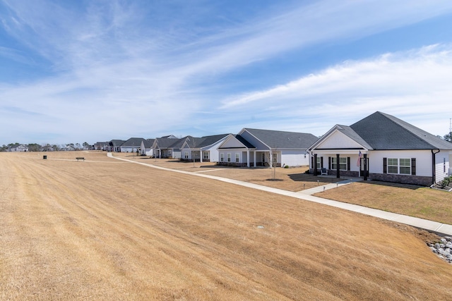 exterior space featuring stone siding, a residential view, and a front lawn