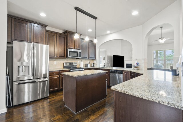5315 Bull St, Augusta, GA 30909 - kitchen with appliances with stainless steel finishes, dark brown cabinetry, arched walkways, light stone counters, and recessed lighting