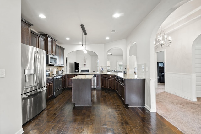 5315 Bull St, Augusta, GA 30909 - kitchen with appliances with stainless steel finishes, dark brown cabinetry, dark wood-style floors, a center island, and a chandelier