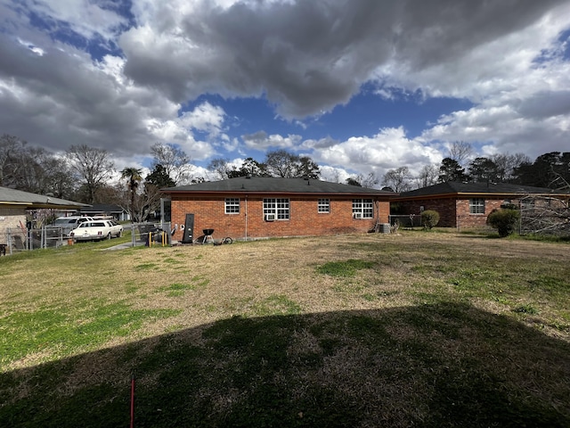 back of house with a yard, brick siding, and fence