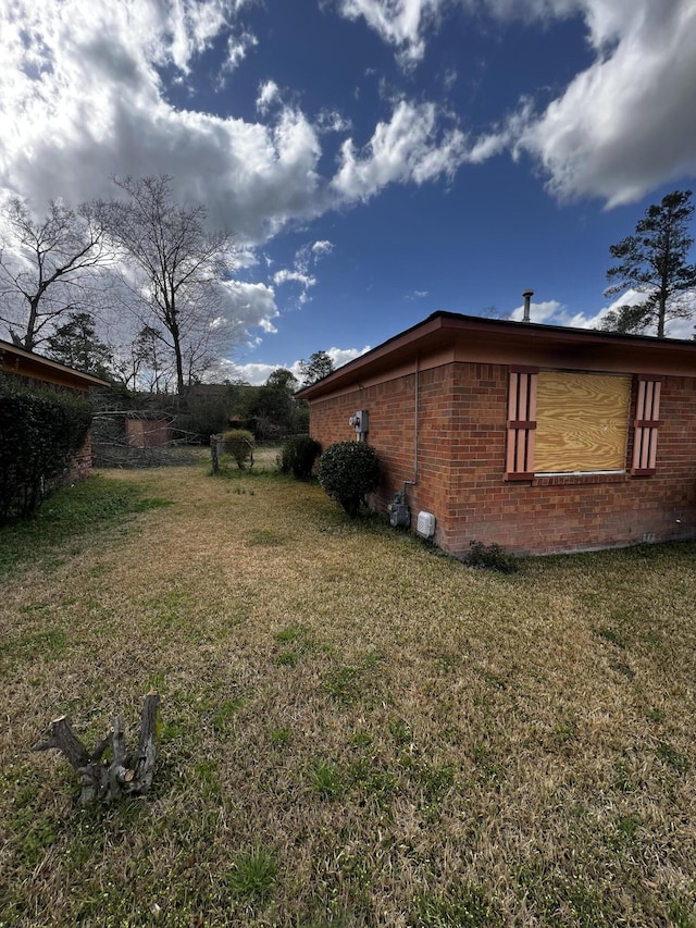 view of home's exterior with brick siding and a lawn