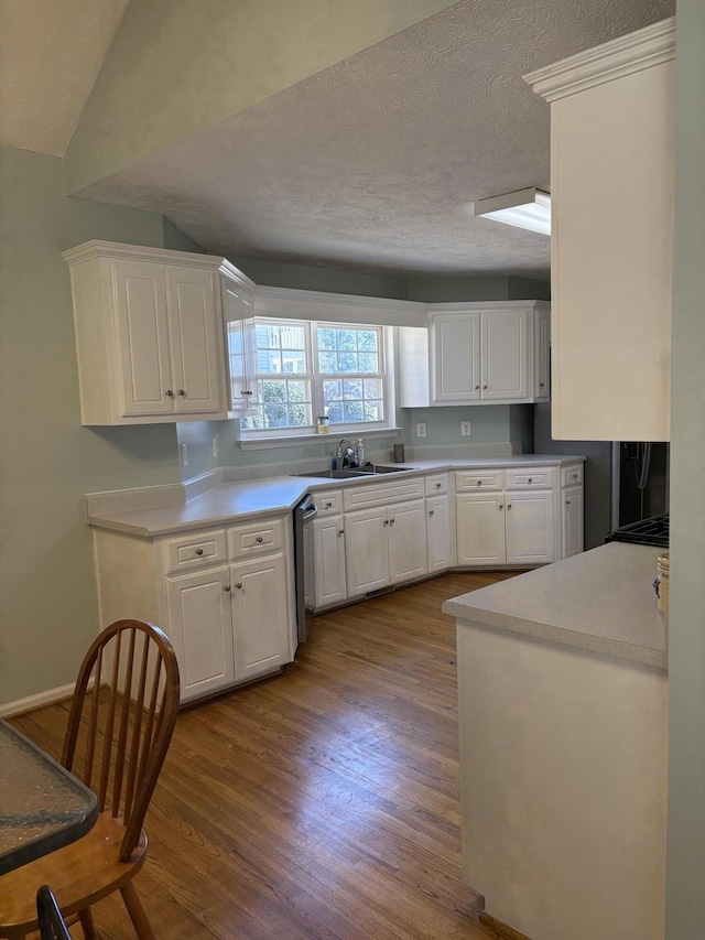 kitchen with a sink, dark wood-type flooring, light countertops, a textured ceiling, and white cabinetry