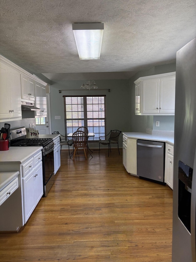 kitchen with white cabinetry, light countertops, wood finished floors, and stainless steel appliances