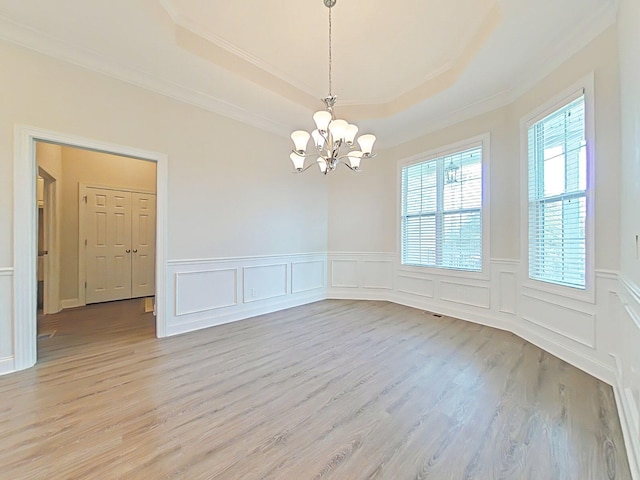 unfurnished dining area with an inviting chandelier, plenty of natural light, a raised ceiling, and light wood-type flooring