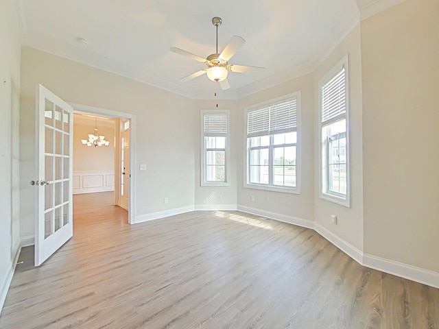 spare room featuring baseboards, ornamental molding, ceiling fan with notable chandelier, and light wood-type flooring