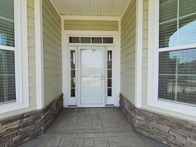 entrance to property featuring covered porch and stone siding