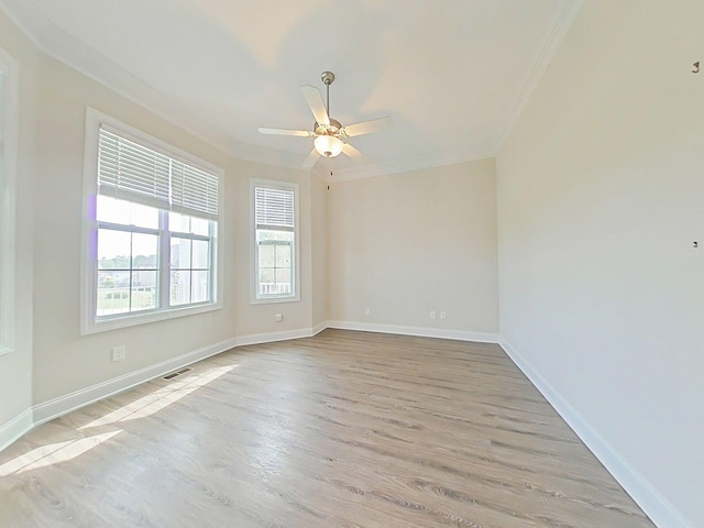 spare room with a ceiling fan, visible vents, crown molding, baseboards, and light wood-style flooring