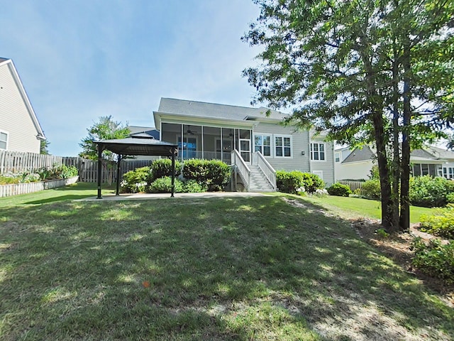 view of front of house featuring ceiling fan, a sunroom, a gazebo, fence, and a front lawn