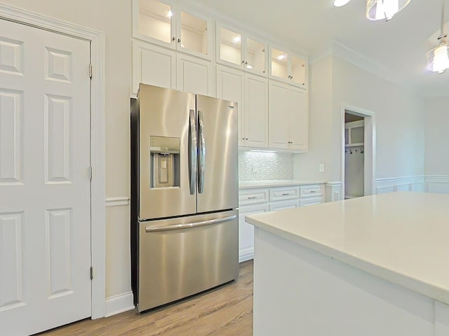 kitchen featuring light wood finished floors, stainless steel fridge with ice dispenser, light countertops, white cabinetry, and glass insert cabinets