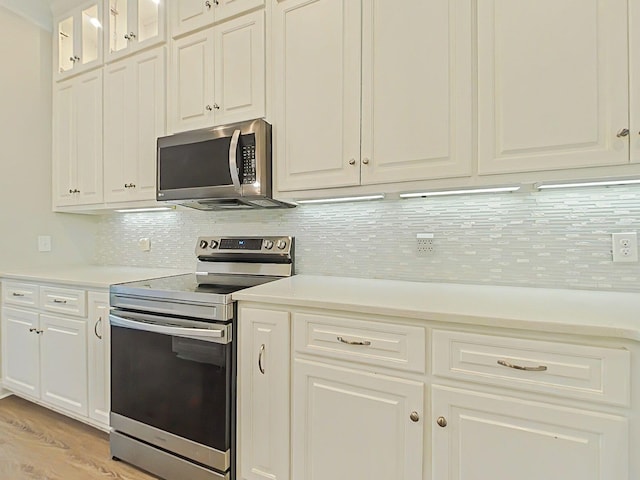 kitchen featuring light countertops, appliances with stainless steel finishes, white cabinets, and backsplash