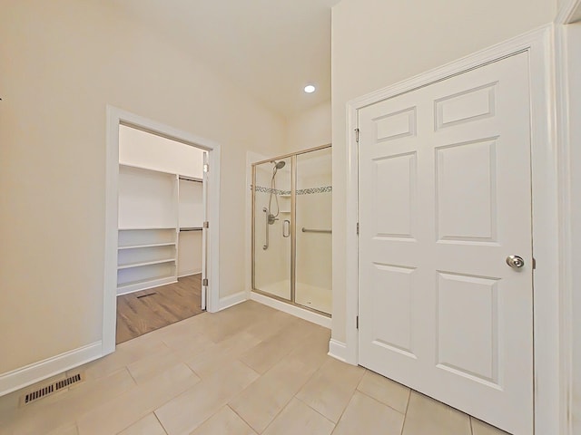 bathroom featuring a walk in closet, recessed lighting, baseboards, a shower stall, and visible vents