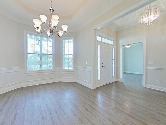 entryway with a wainscoted wall, ornamental molding, wood finished floors, and a notable chandelier