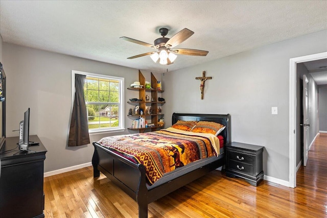 bedroom featuring light wood-style floors, baseboards, and a textured ceiling