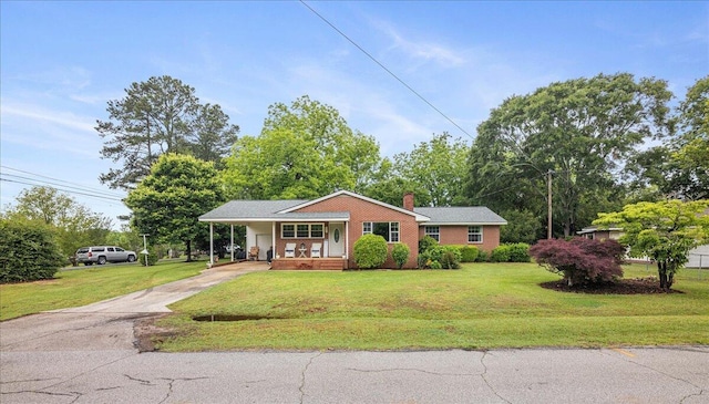 single story home featuring an attached carport, a porch, concrete driveway, a front yard, and a chimney