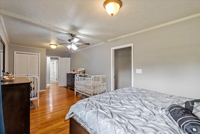 bedroom featuring ornamental molding, wood finished floors, baseboards, and a textured ceiling