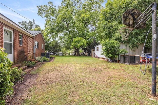 view of yard with a trampoline and central AC