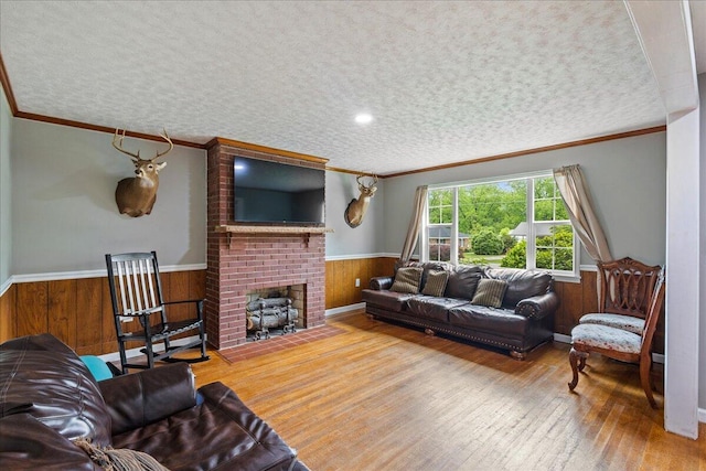 living room with wooden walls, wainscoting, hardwood / wood-style flooring, a textured ceiling, and crown molding