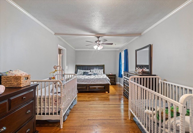 bedroom with crown molding, baseboards, wood finished floors, a textured ceiling, and a ceiling fan