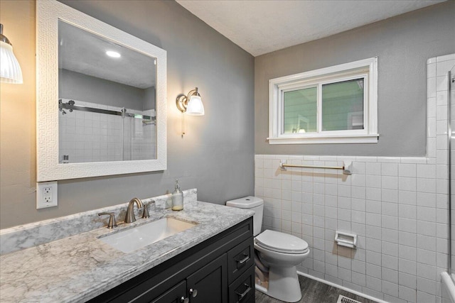 full bath with walk in shower, toilet, vanity, wood finished floors, and tile walls