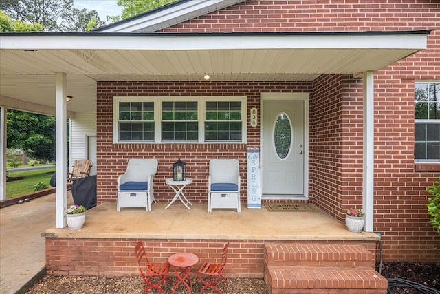 property entrance with brick siding and a porch