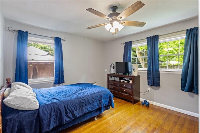 bedroom with light wood-style flooring, baseboards, and ceiling fan