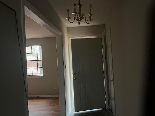 doorway to outside with a textured ceiling and a chandelier