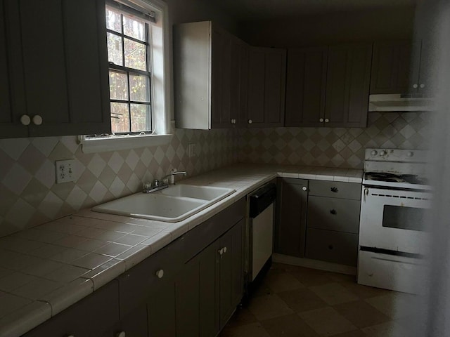 kitchen with gray cabinetry, sink, tile countertops, white appliances, and decorative backsplash