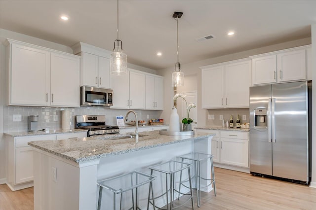 kitchen with appliances with stainless steel finishes, white cabinetry, hanging light fixtures, and sink