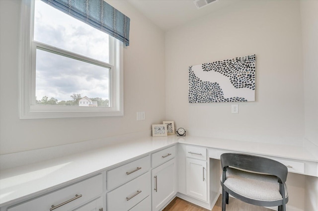 office area with light wood-type flooring, built in desk, and a wealth of natural light