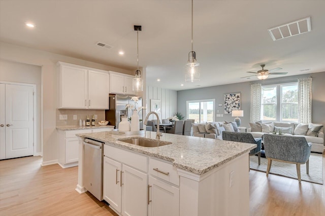 kitchen with ceiling fan, sink, stainless steel appliances, a kitchen island with sink, and white cabinets