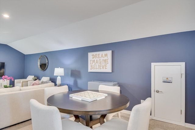 dining space featuring light colored carpet and vaulted ceiling