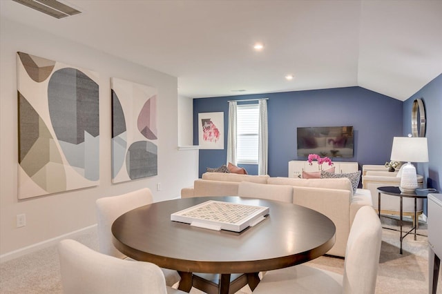 dining space featuring light colored carpet and vaulted ceiling