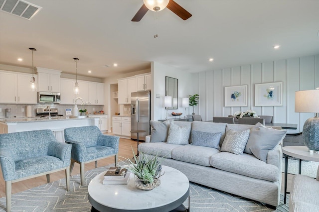 living room with light wood-type flooring and ceiling fan