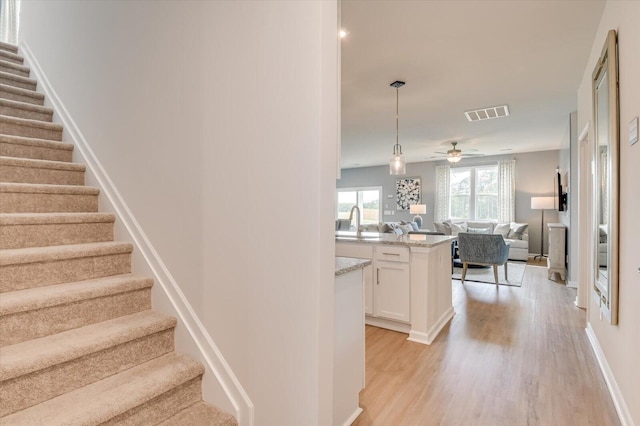 staircase with ceiling fan, sink, and wood-type flooring