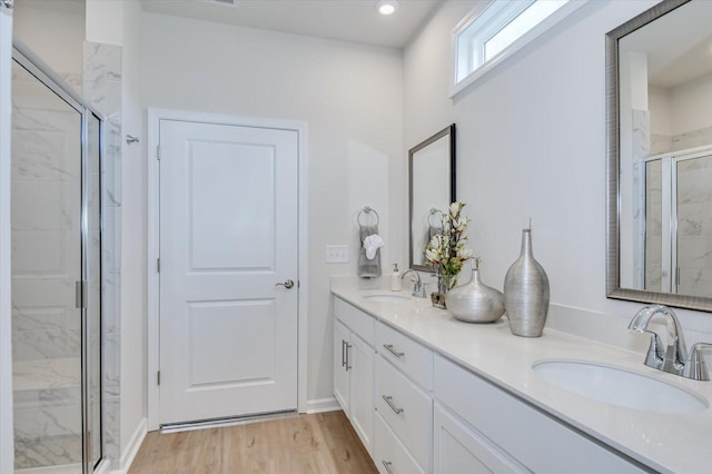 bathroom with hardwood / wood-style flooring, vanity, and a shower with door