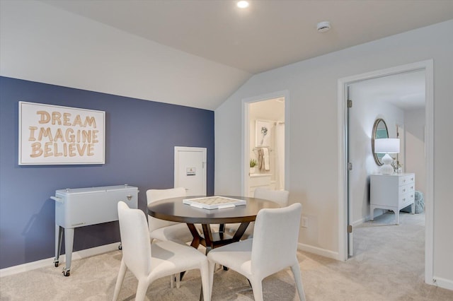 dining room featuring light colored carpet and lofted ceiling