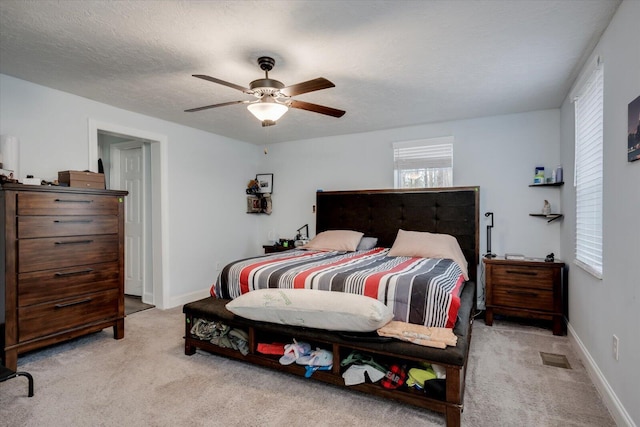 carpeted bedroom with ceiling fan and a textured ceiling