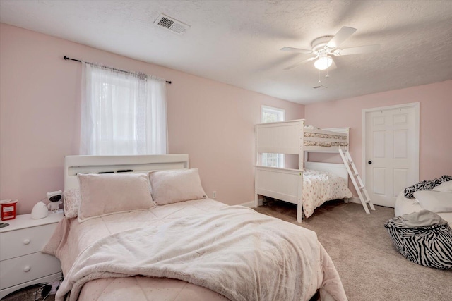 carpeted bedroom with ceiling fan and a textured ceiling