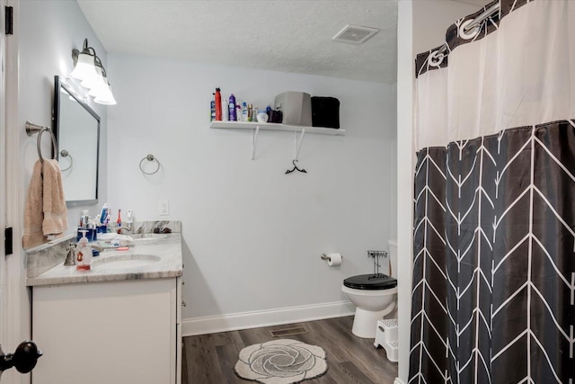 bathroom featuring toilet, wood-type flooring, a textured ceiling, vanity, and curtained shower