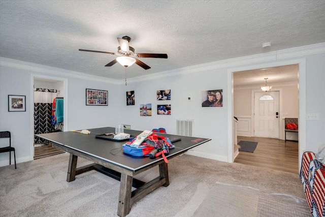 recreation room featuring crown molding, a textured ceiling, and carpet flooring