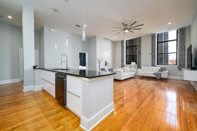 kitchen featuring decorative light fixtures, light wood-type flooring, white cabinetry, and sink