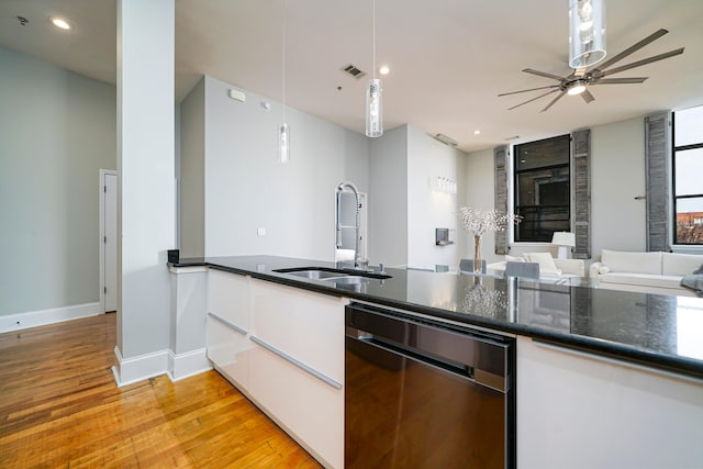 kitchen with light wood-type flooring, sink, black dishwasher, white cabinetry, and hanging light fixtures