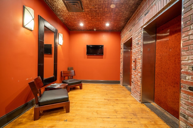 hallway with light hardwood / wood-style flooring and brick wall