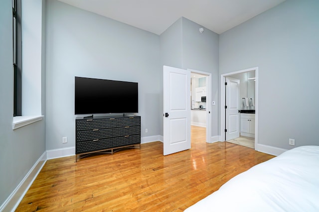 bedroom with hardwood / wood-style floors, a high ceiling, and ensuite bath