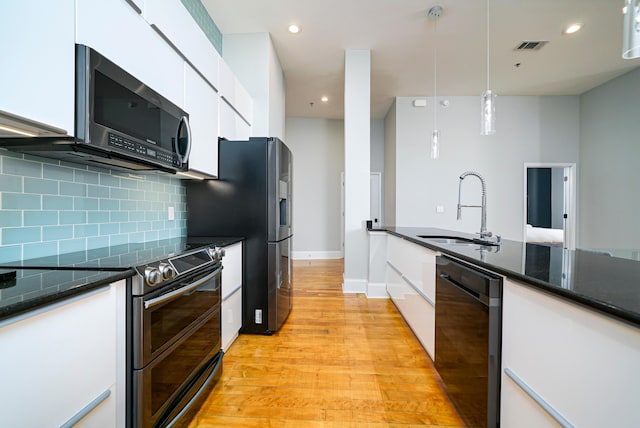 kitchen featuring appliances with stainless steel finishes, tasteful backsplash, sink, decorative light fixtures, and white cabinetry