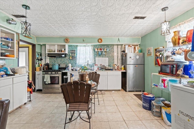 kitchen with plenty of natural light, white cabinetry, stainless steel appliances, and hanging light fixtures