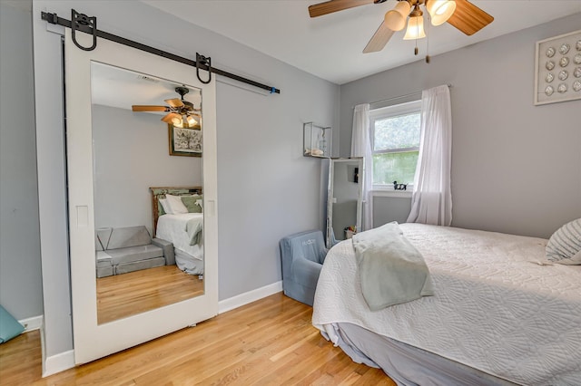 208 Elm St, Grovetown, GA 30813 - bedroom with a barn door, light wood finished floors, a ceiling fan, and baseboards