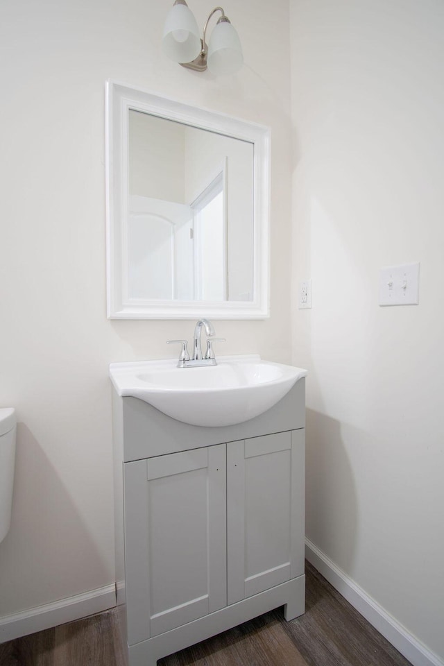 bathroom with toilet, vanity, and wood-type flooring